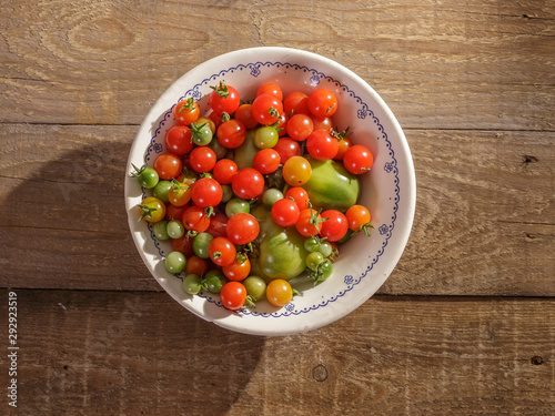 Red and green cherry tomatoes in a plate on the table.