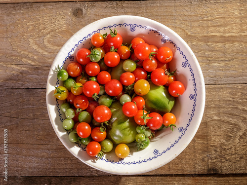 Red and green cherry tomatoes in a plate on the table.