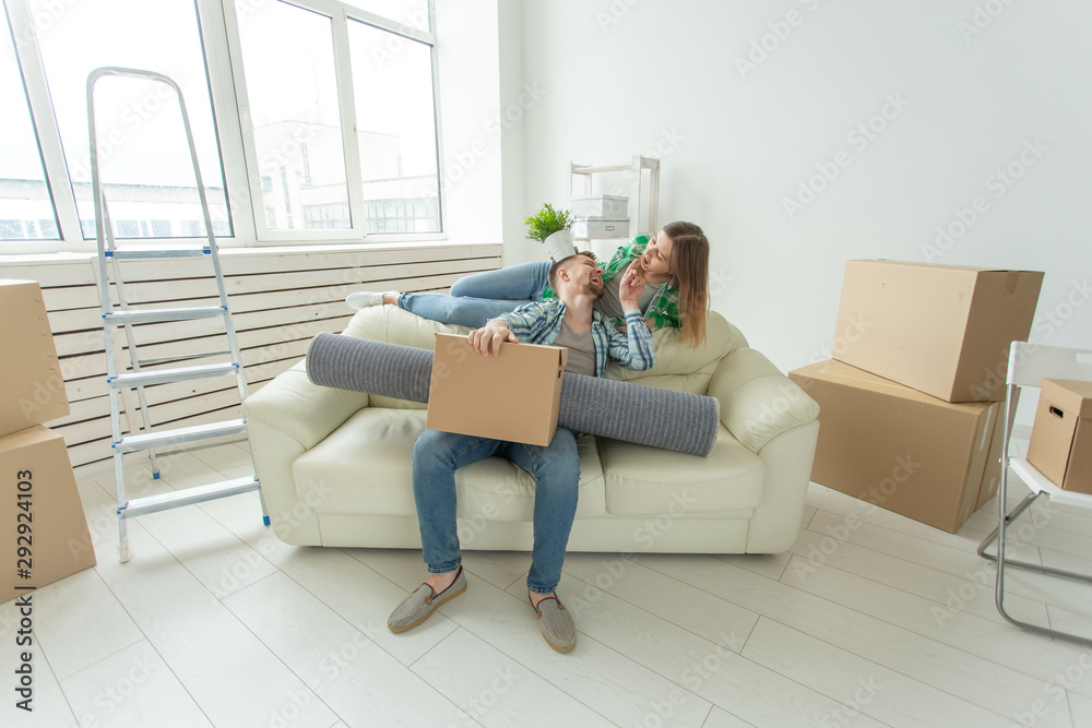 Cheerful young couple rejoices in moving to a new home laying out their belongings in the living room. Concept of housewarming and mortgages for a young family Cheerful young couple rejoices in moving to a new home laying out their belongings in the living room. Concept of housewarming and mortgages for a young family