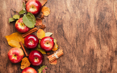 Autumn food background. Ripe apples with nuts, fallen leaves and cinnamon on rustic wooden table. Top view. Copy space