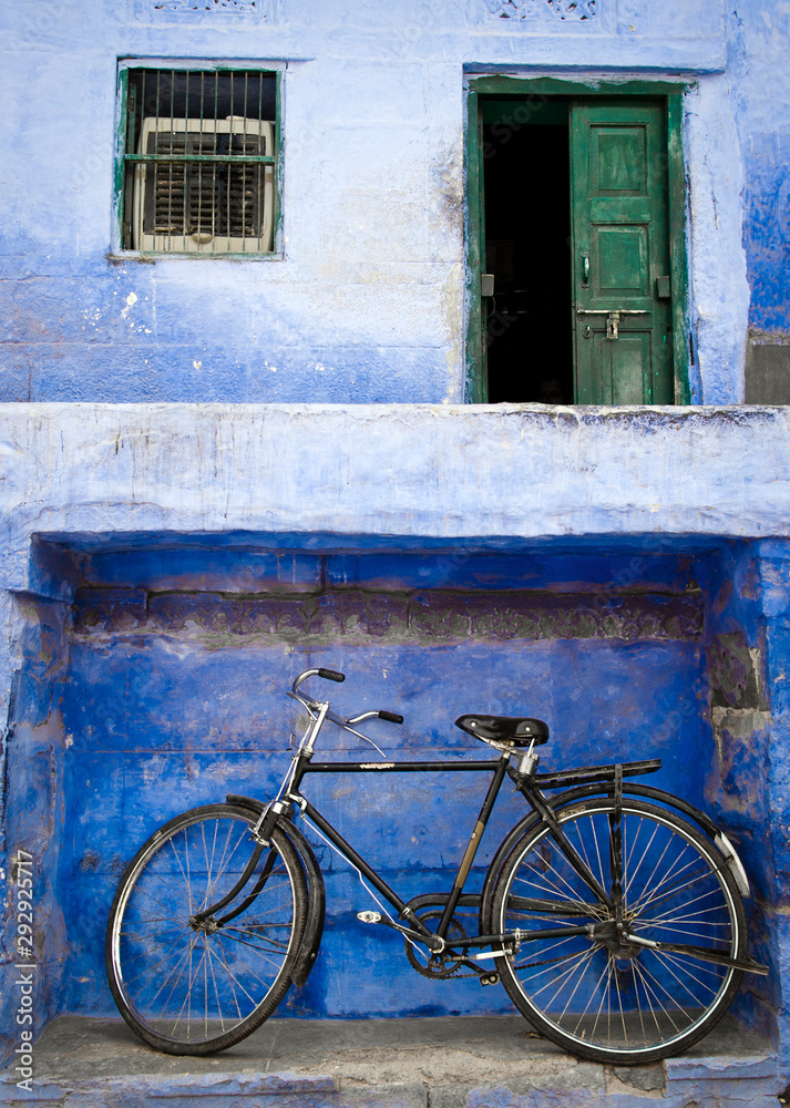 English bike parked out of a blue painted house facade in the old town of  Jodhpur, Rajasthan, India