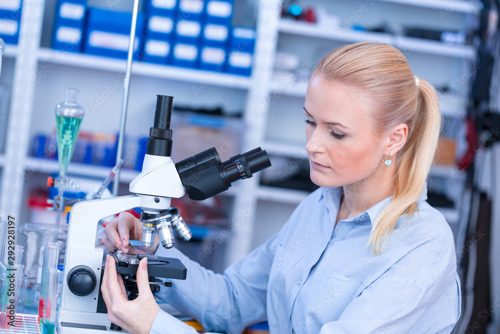 Girl with a slide for the microscope University Hospital. Attractive young scientist  looking at the microscope slide in the forensic laboratory