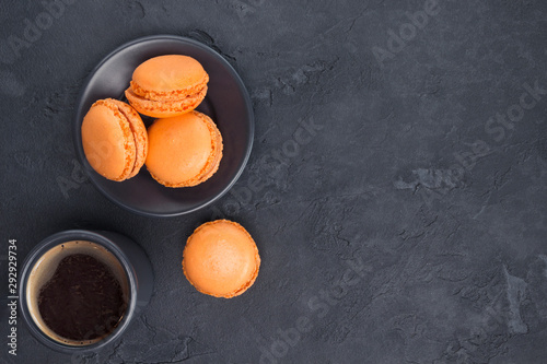Orange macaroons, black coffee on gray concrete background. Recipe, Halloween concept. Top view, flat lay, copy space