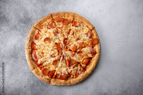 Delicious hot homemade Pepperoni pizza on the wooden table. Pepperoni Pizza - Fresh homemade pizza with pepperoni, cheese and tomato sauce on rustic black stone background with copy space.