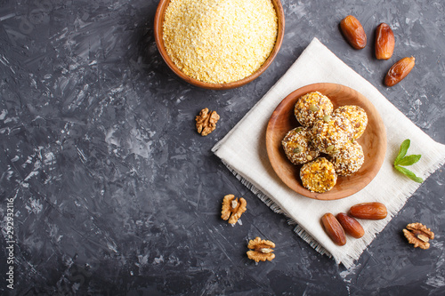 Energy ball cakes with dried apricots, cornflakes, sesame, linen, walnuts and dates on a black concrete background, top view, copy space.