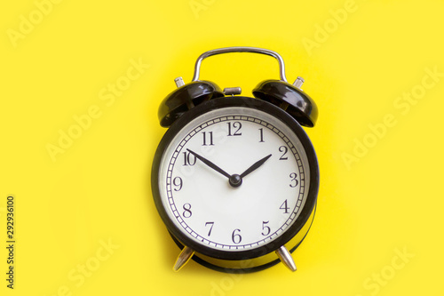 Black alarm clock on yellow background