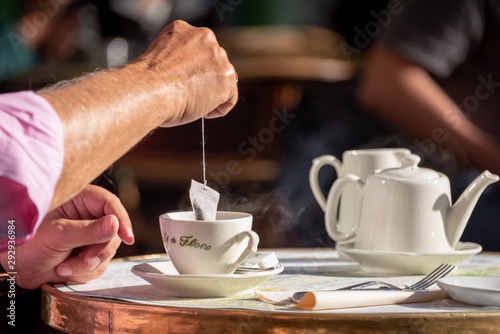 Photography Mans arm dipping tea bag in saucer at a Paris cafe in the morningP
