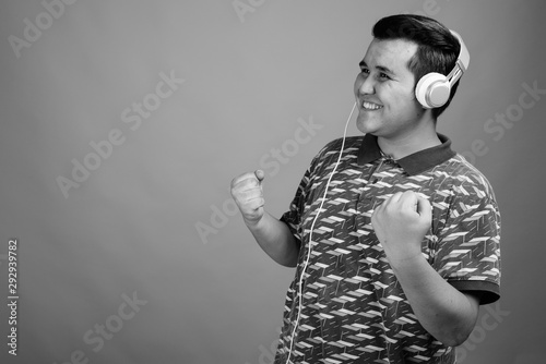 Young multi-ethnic man listening to music against gray background