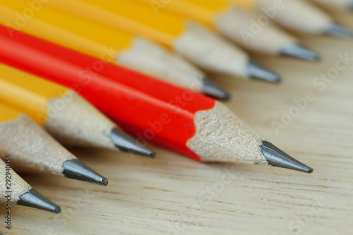 Red pencil standing out from croud of yellow pencils - Think different and leadership concept photo