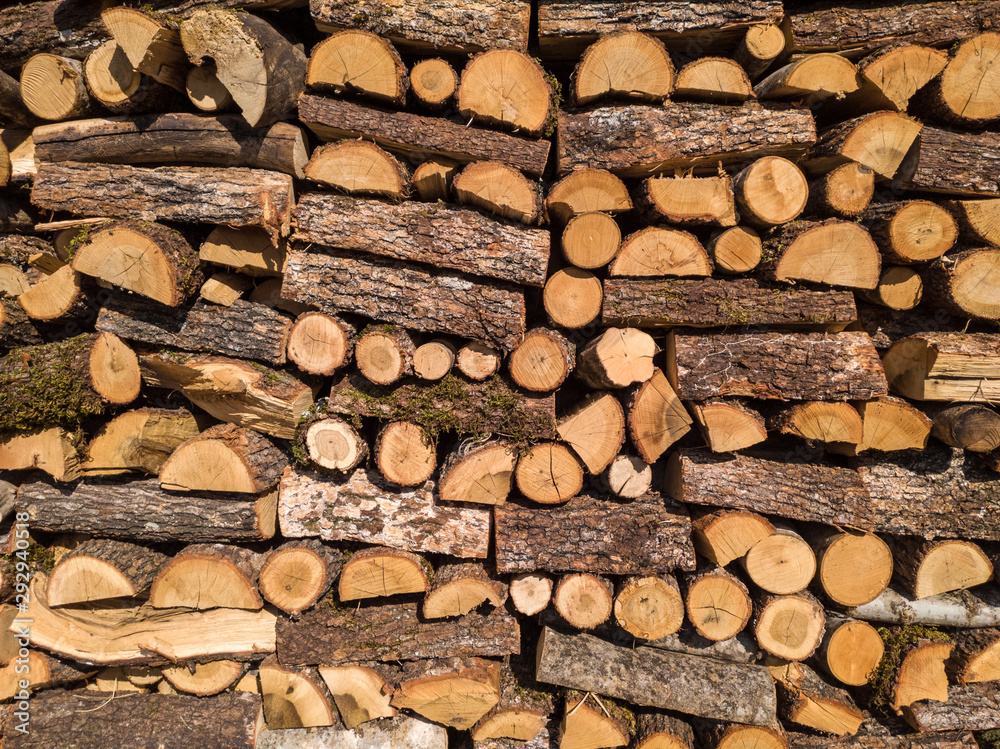 Stacked chopped logs of firewood with bark on a sunny day. Stacked chopped logs of firewood with bark on a sunny day.