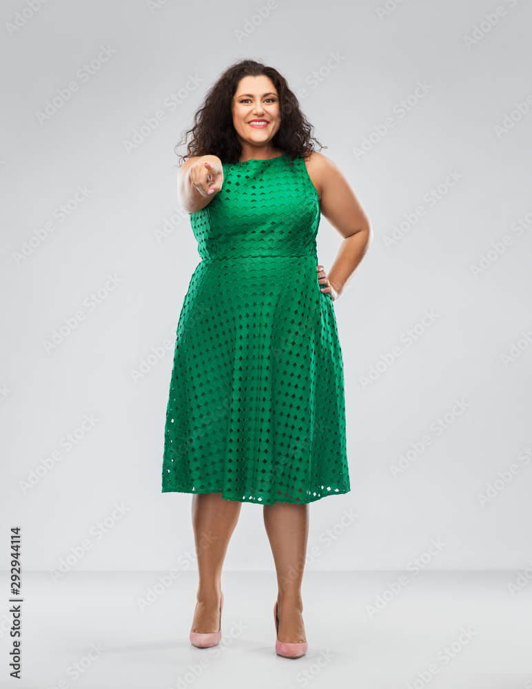 people and portrait concept - happy woman in green dress pointing finger to camera over grey background people and portrait concept - happy woman in green dress pointing finger to camera over grey background