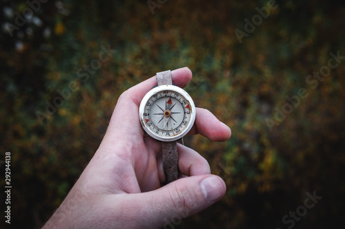 Man hand holding a old compass with broken glass. Travel concept, path selection, navigation, tourism, hiking. Autumn background. crack on the glass as disappointment and cancellation of plans.