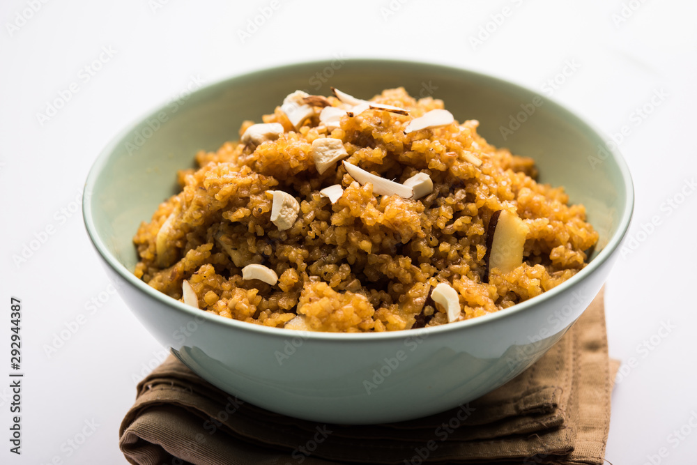 Wheat Laapsi/Lapsi/Shira/Halwa is an Indian sweet dish made of broken wheat or Daliya pieces and ghee along with nuts, raisins and dried fruits. It's a healthy food. served in a bowl, selective focus