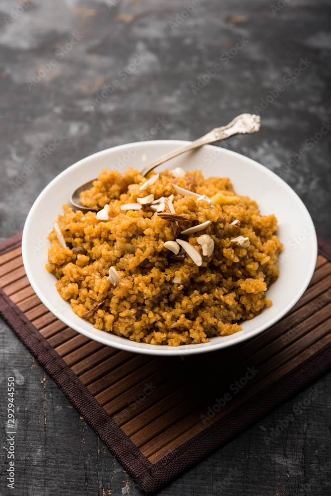 Wheat Laapsi/Lapsi/Shira/Halwa is an Indian sweet dish made of broken wheat or Daliya pieces and ghee along with nuts, raisins and dried fruits. It's a healthy food. served in a bowl, selective focus Wheat Laapsi/Lapsi/Shira/Halwa is an Indian sweet dish made of broken wheat or Daliya pieces and ghee along with nuts, raisins and dried fruits. It's a healthy food. served in a bowl, selective focus