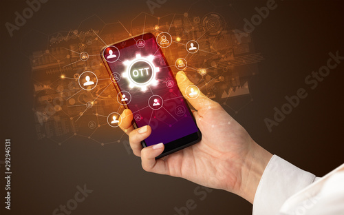 Female hand holding smartphone with OTT abbreviation, modern technology concept photo