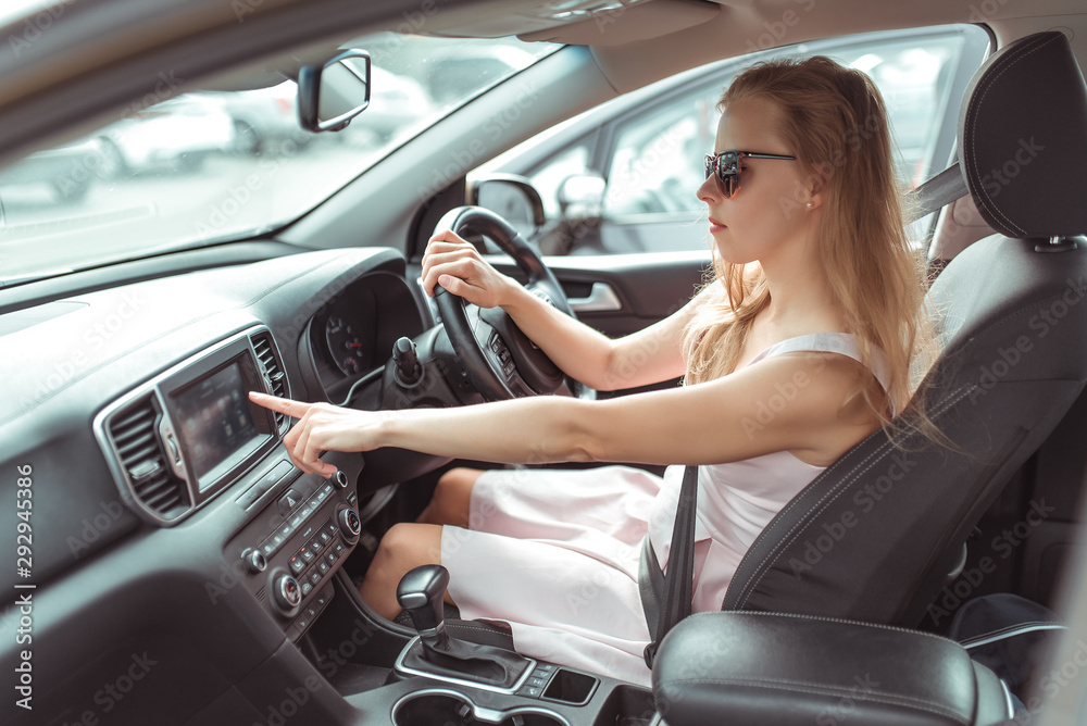 custom made wallpaper toronto digitalgirl in car selects application on touch screen, navigation application on Internet, strapped holds wheel, left-hand traffic, wheel on right side. Woman in summer sunglasses in city.