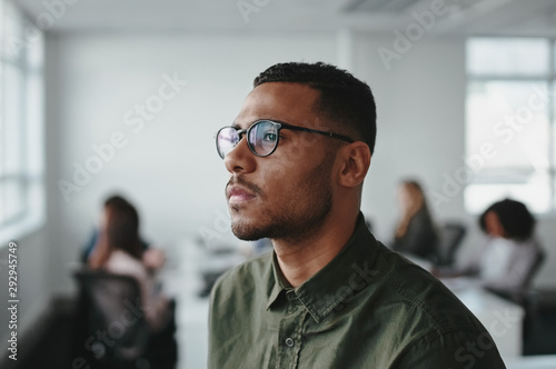 Close-up of a young african american business man entrepreneur wearing eyeglasses contemplating in office