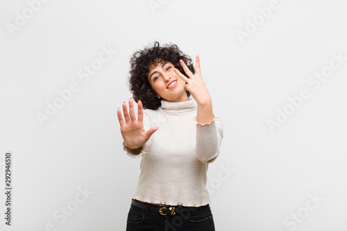 young pretty afro woman smiling and looking friendly, showing number eight or eighth with hand forward, counting down photo