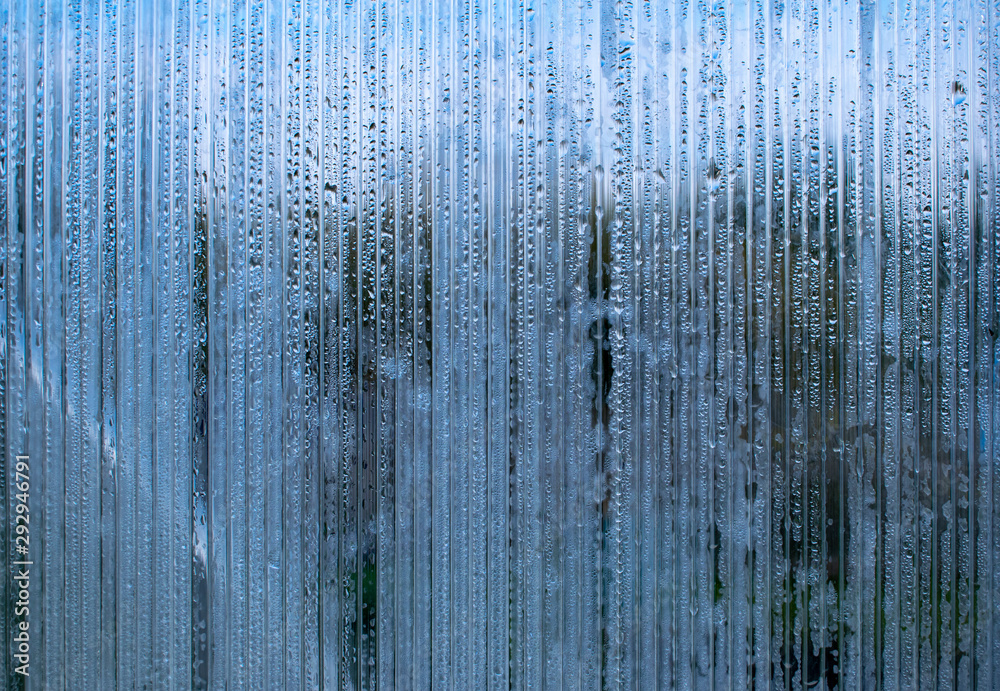 Drops of autumn rain slowly flow down the glass door creating a sad ...