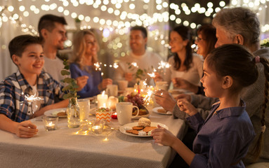 celebration, holidays and christmas concept - happy family with sparklers having fun at dinner party at home