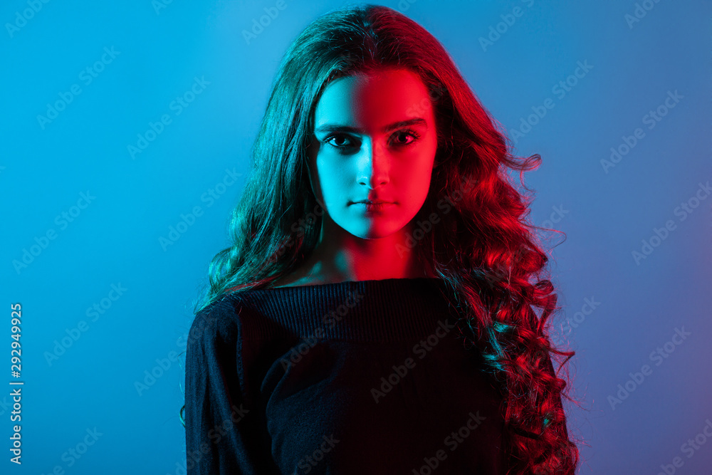 Portrait of a young girl with red and blue light on her face.