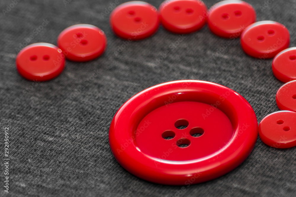 Bright red buttons. Gray fabric. Blurred background. The concept of the clothing industry and decor. Bright red buttons. Gray fabric. Blurred background. The concept of the clothing industry and decor.