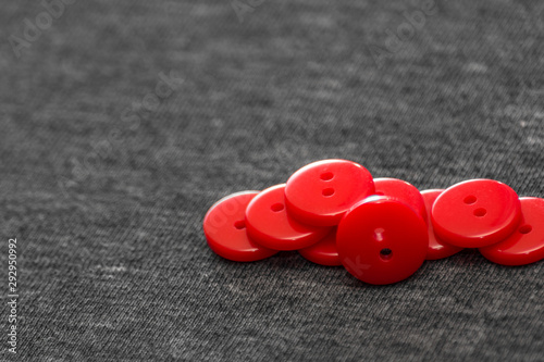 Bright red buttons. Gray fabric. Blurred background. The concept of the clothing industry and decor.