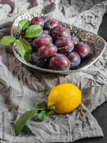 Fresh organic plums and lemon on a metal vintage dish. Still life of ripe and juicy fruits