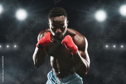 Young fighter in boxing stance staying on stadium arena © Prostock-studio