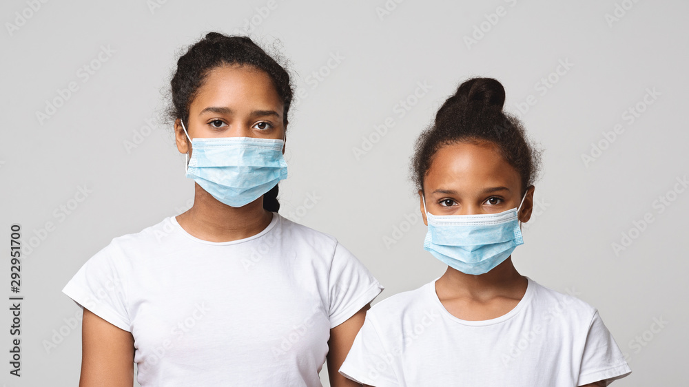 Two young sisters wearing medical masks over grey studio background Two young sisters wearing medical masks over grey studio background