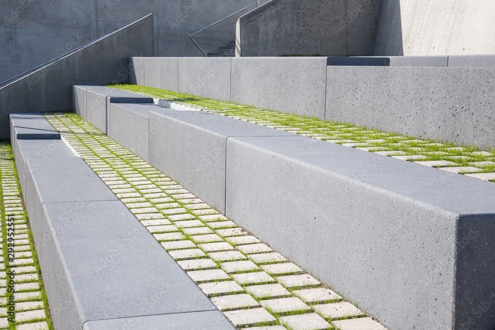 Fototapeta premium Moderner Garten und Landschaftsbau: Aussen Treppen und Stufen zum Sitzen aus Beton- und Natursteinen mit Gras Füllung