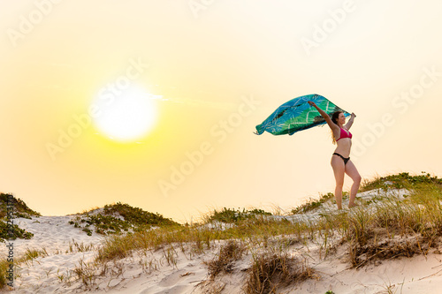 Beautiful model holding colorful yoke in dune during sunset.