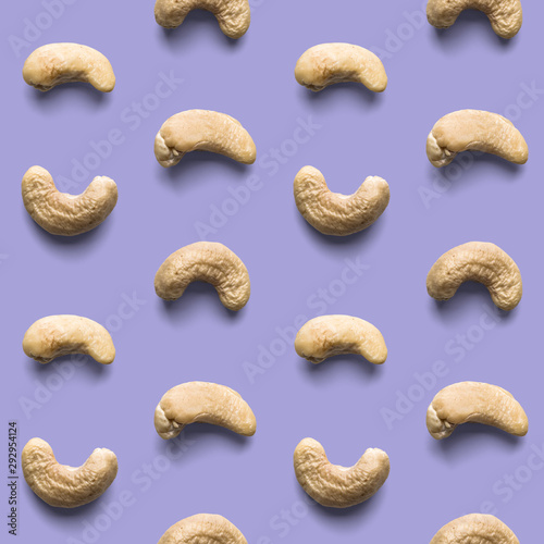 Fresh healthy tasty nutritious cashew on light violet background. Top view. Flat layout. Seamless pattern