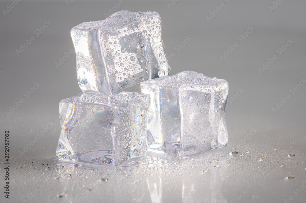 Close up of three wet ice cubes on a white background with reflection. Close up of three wet ice cubes on a white background with reflection.