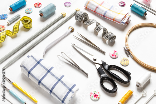 Sewing flat lay composition with threads, fabrics, scissors, buttons and sewing accessories on a white background, flat lay isometry.Set of sewing thread and accessories long banner