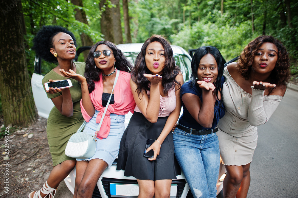 Group of five happy african american girls sitting on a car hood. Group of five happy african american girls sitting on a car hood.