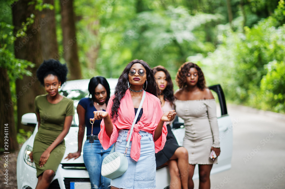 Fototapeta premium Group of five happy african american girls posed against car, one of them show keys.