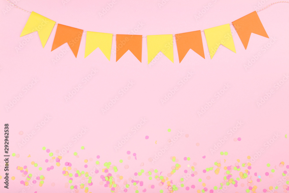 Colorful confetti and paper flags on pink background