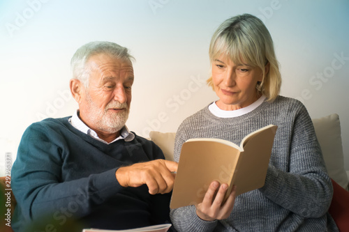 Senior couple reading book in living room