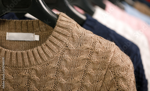 Collection of cable knit sweaters on hanger rack in a store for sale