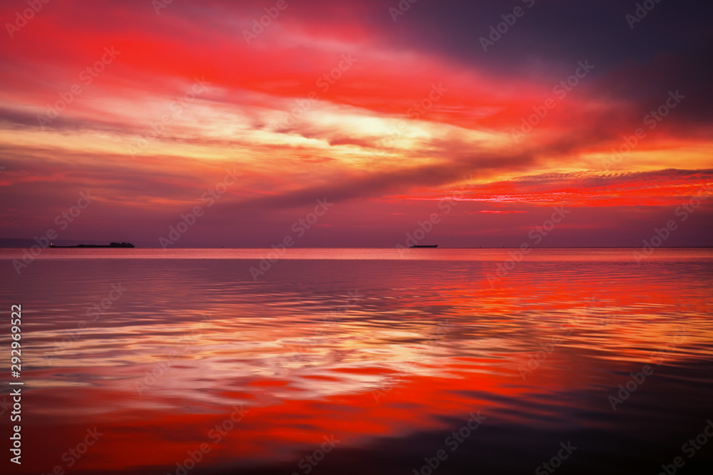Fiery dramatic landscape with the sea, beautiful sky and ships. Dawn. small waves, almost calm.