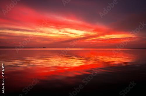 Fiery dramatic landscape with the sea  beautiful sky and ships. Dawn. small waves  almost calm.