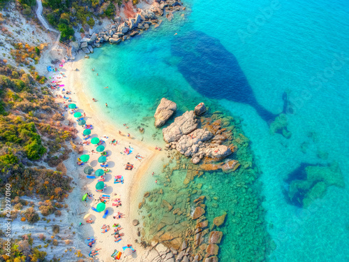 Aerial view of an emerald and transparent Mediterranean sea with a white beach full of beach umbrellas and tourists who relax and swim. Xigia beach in Zakynthos - Greece. 