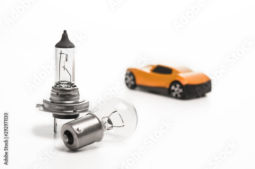 Car light bulb on a white background in front of a yellow car. Car lamps. The concept of service tinning a car.