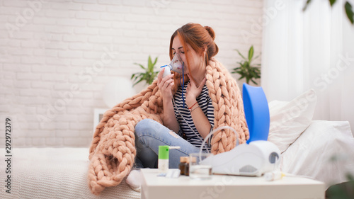 Young woman doing inhalation with a nebulizer at home photo