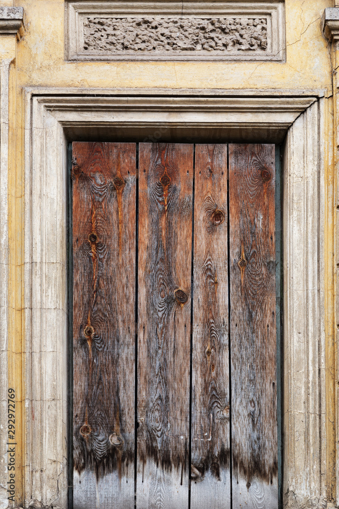Texture of old painted boards with which the window opening of a dilapidated building is boarded up.