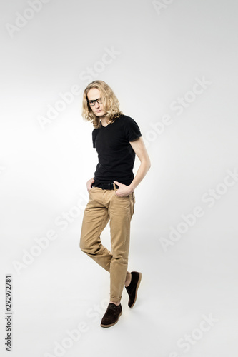 A young handsome guy spectacled with long blonde hair, isolated on a light background.