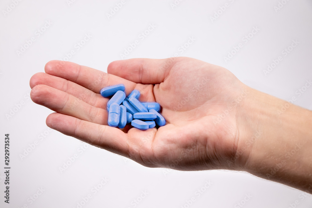 Blue pills in man`s hand on white background