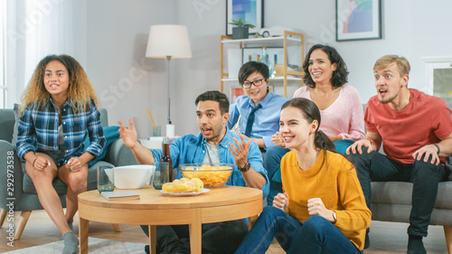 At Home Diverse Group Friends Watching TV Together, Eating Snacks and Drinking Beverage. They Probably Watching Sports Game or Fun Movie.