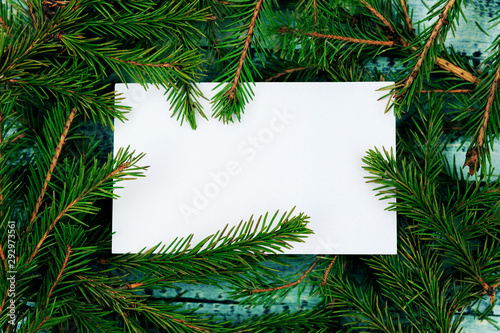 Christmas texture on a blue wooden background surrounded by spruce branches. White form with a place for recording on branches.